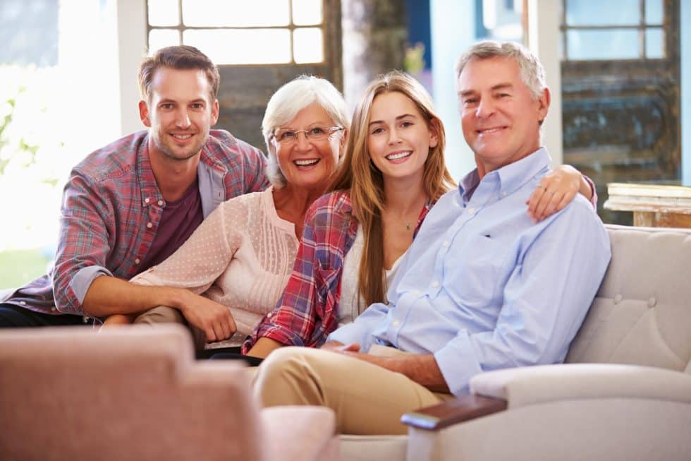 Family of four smiling on couch at home