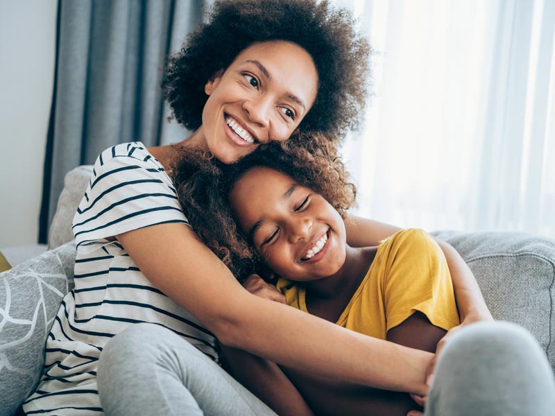 mother and young daughter hugging on couch