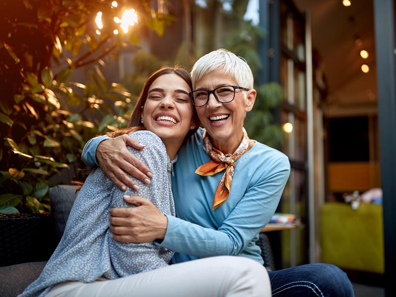 mother and adult daughter hugging and smiling