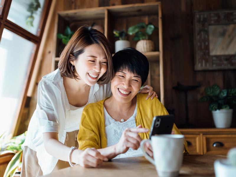 mother and daughter smiling and looking at phone