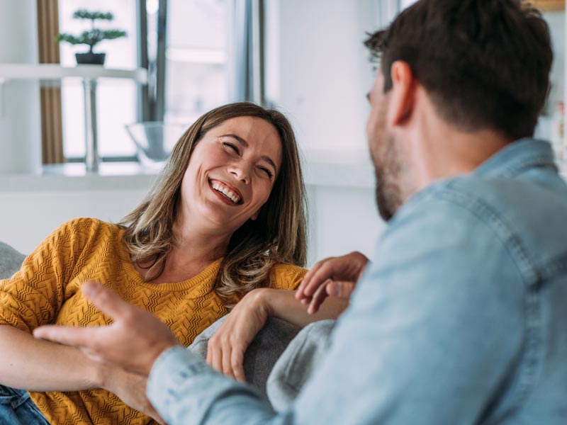 woman sitting on couch laughing