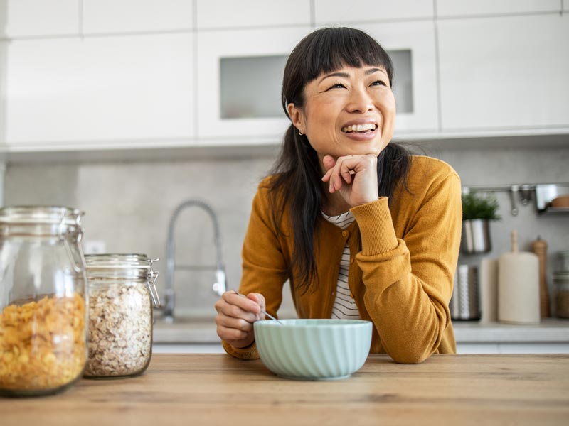 woman smiling and eating bowl of cereal