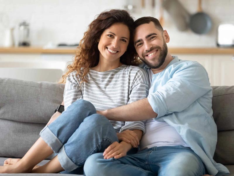 smiling young couple sitting on couch